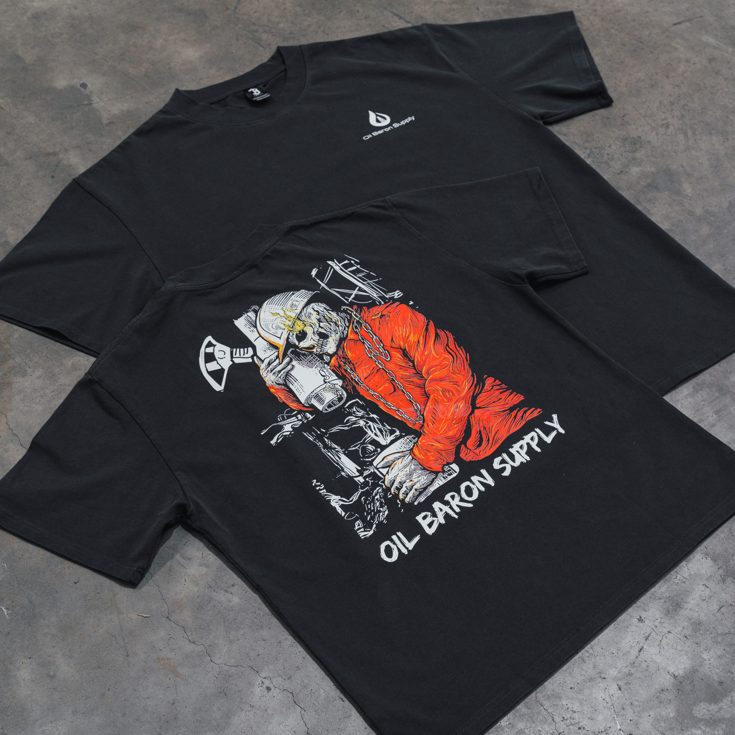 Black t-shirt with graphic design and 'Oil Baron Supply' text on a concrete surface