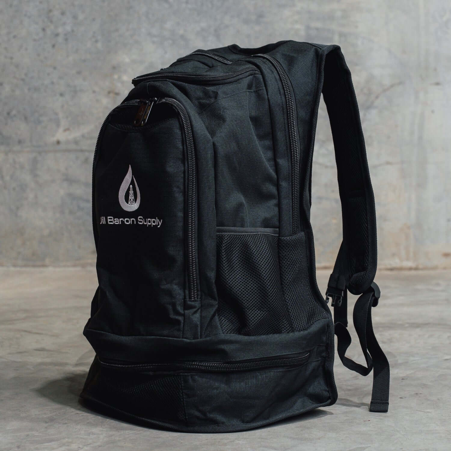Black backpack with Oil Baron Supply logo on a grey background