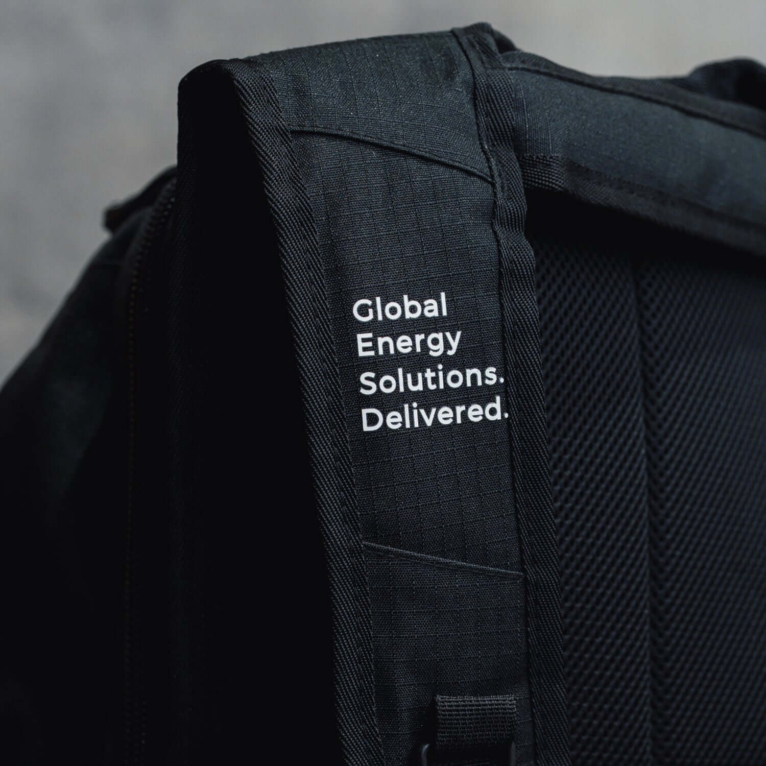 Black backpack with 'Global Energy Solutions. Delivered.' text on a gray background