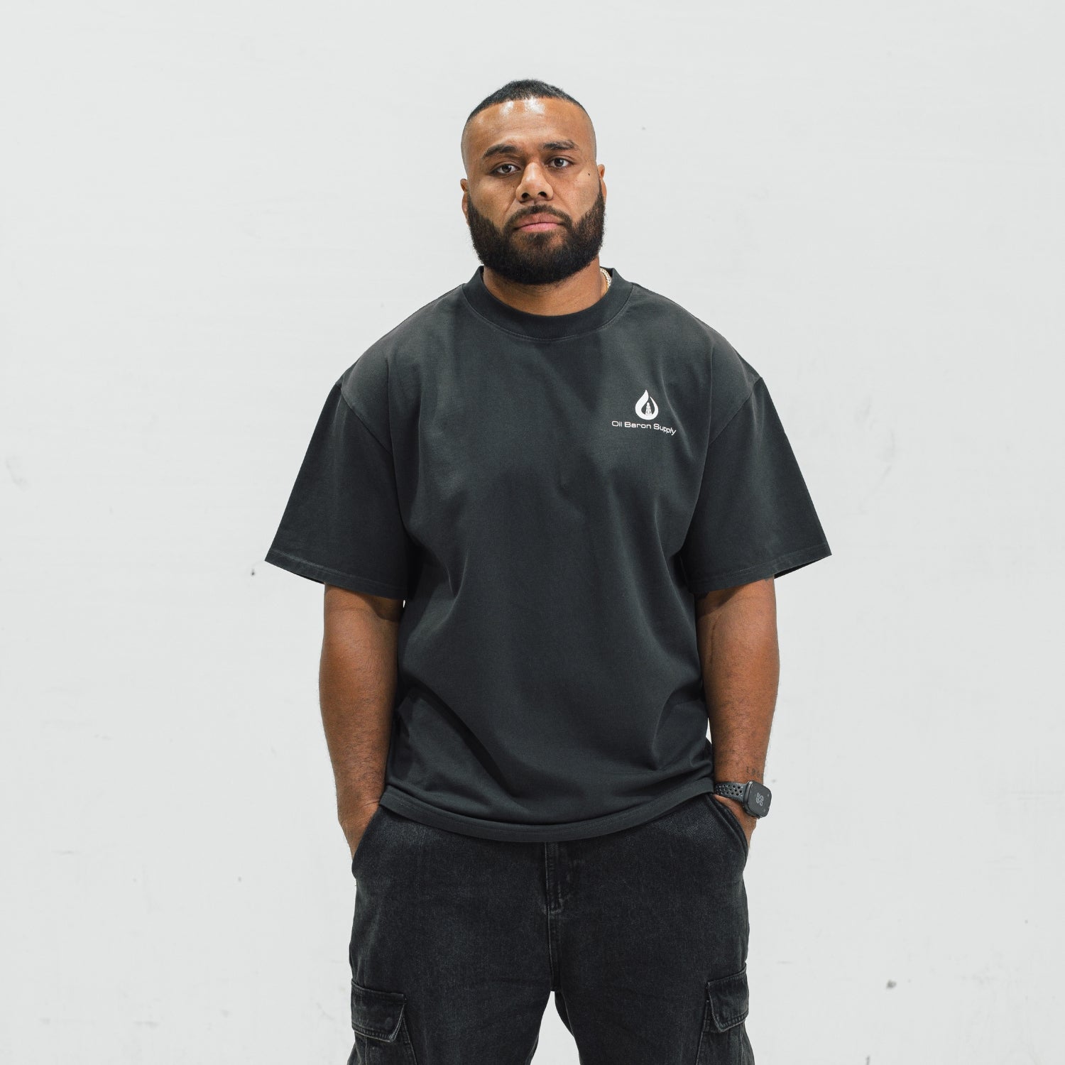 Man wearing a black t-shirt with an oil baron supply logo on a white background