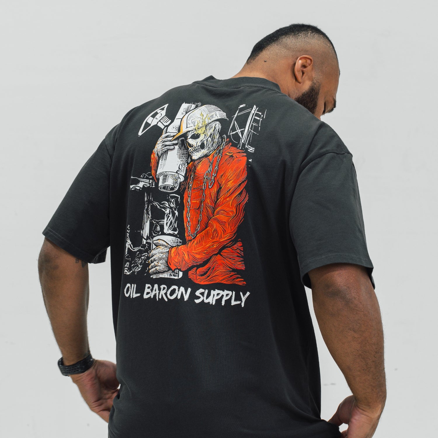 Person wearing a black t-shirt with a graphic design on the back, featuring the text 'Oil Baron Supply'.
