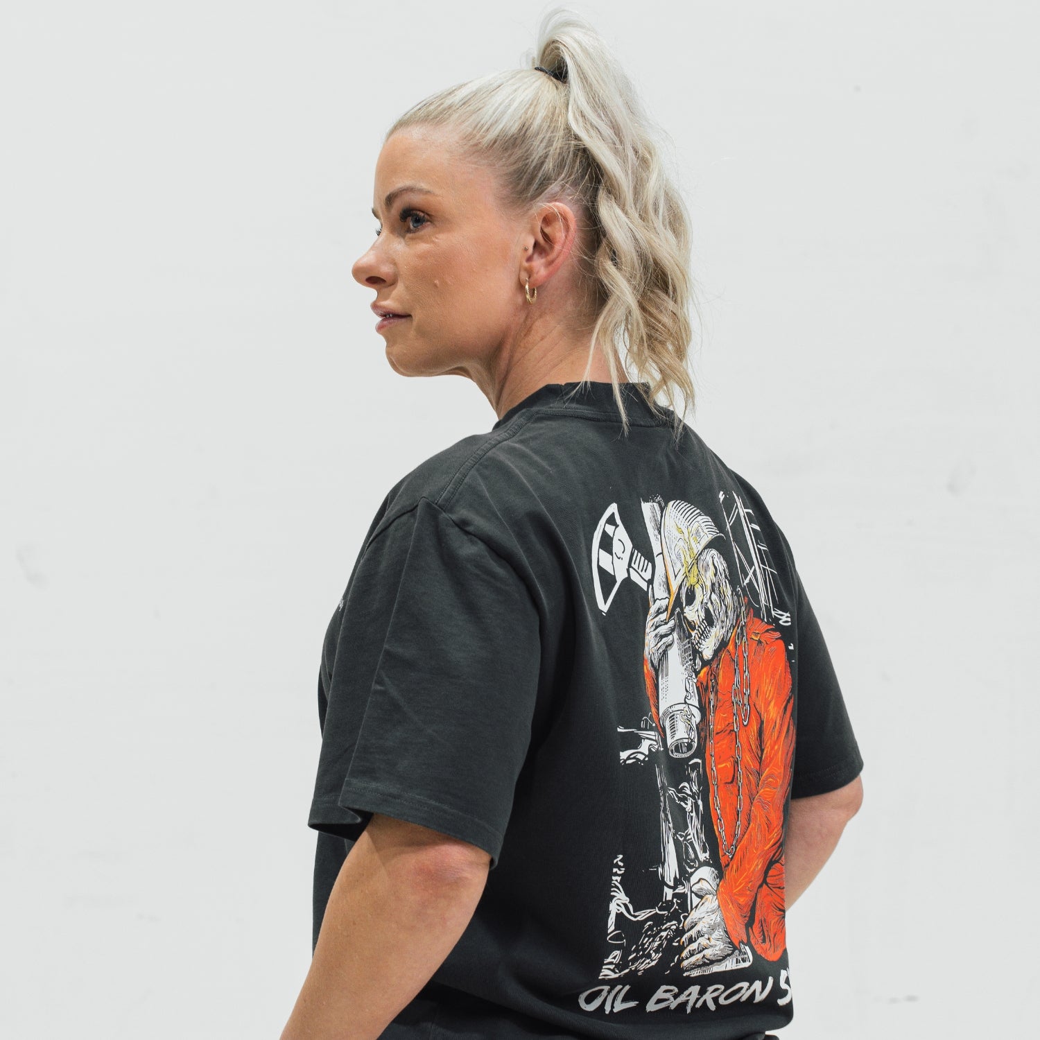 Person wearing a black t-shirt with a graphic design on the back, standing against a white background