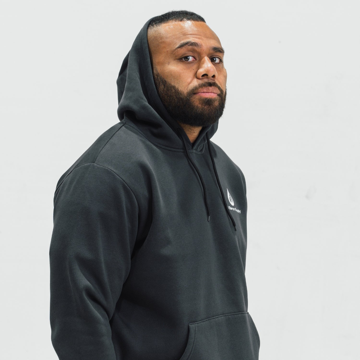 Man wearing a black hoodie with an oil baron supply logo on a light gray background