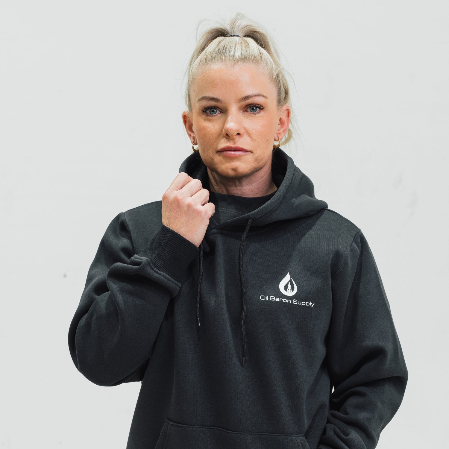 Person wearing a black hoodie with an oil baron supply logo on a plain background