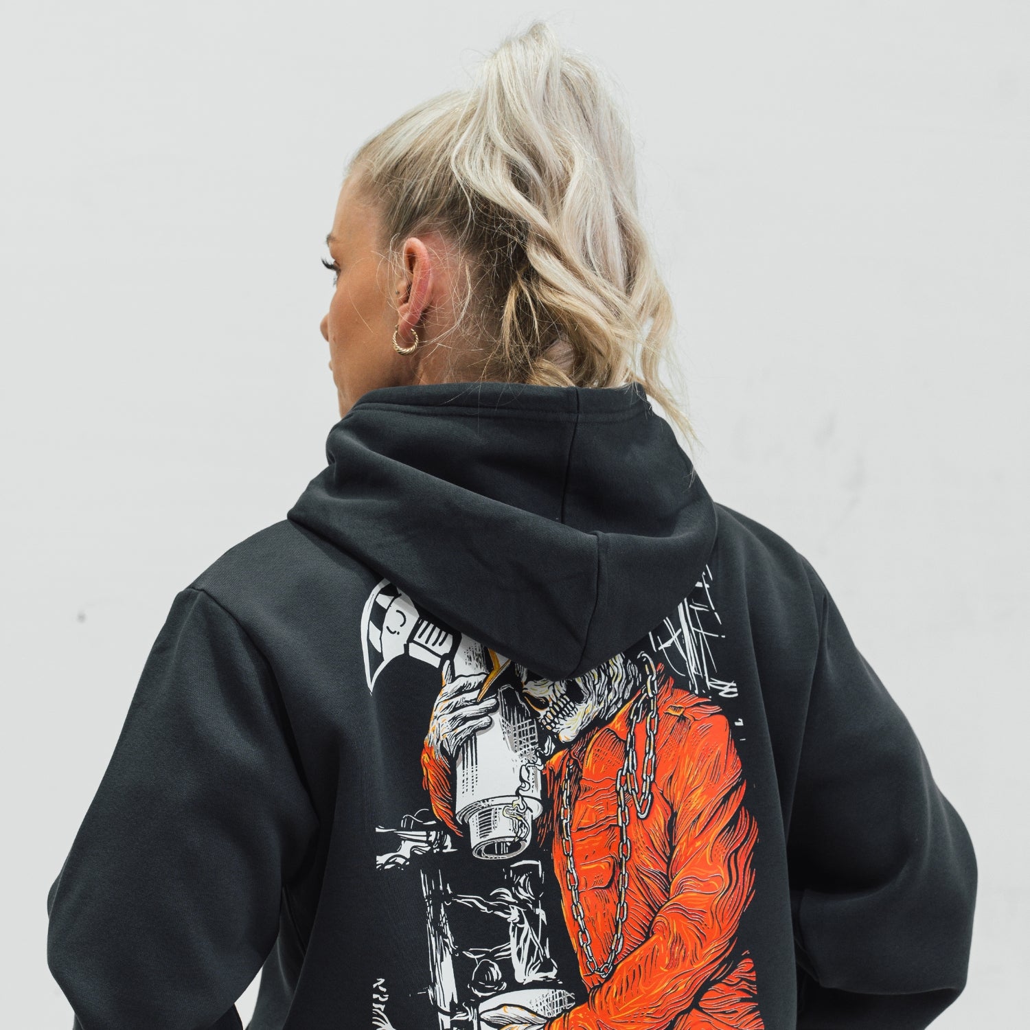 Person wearing a black hoodie with Roughneck designs on the back against a white background