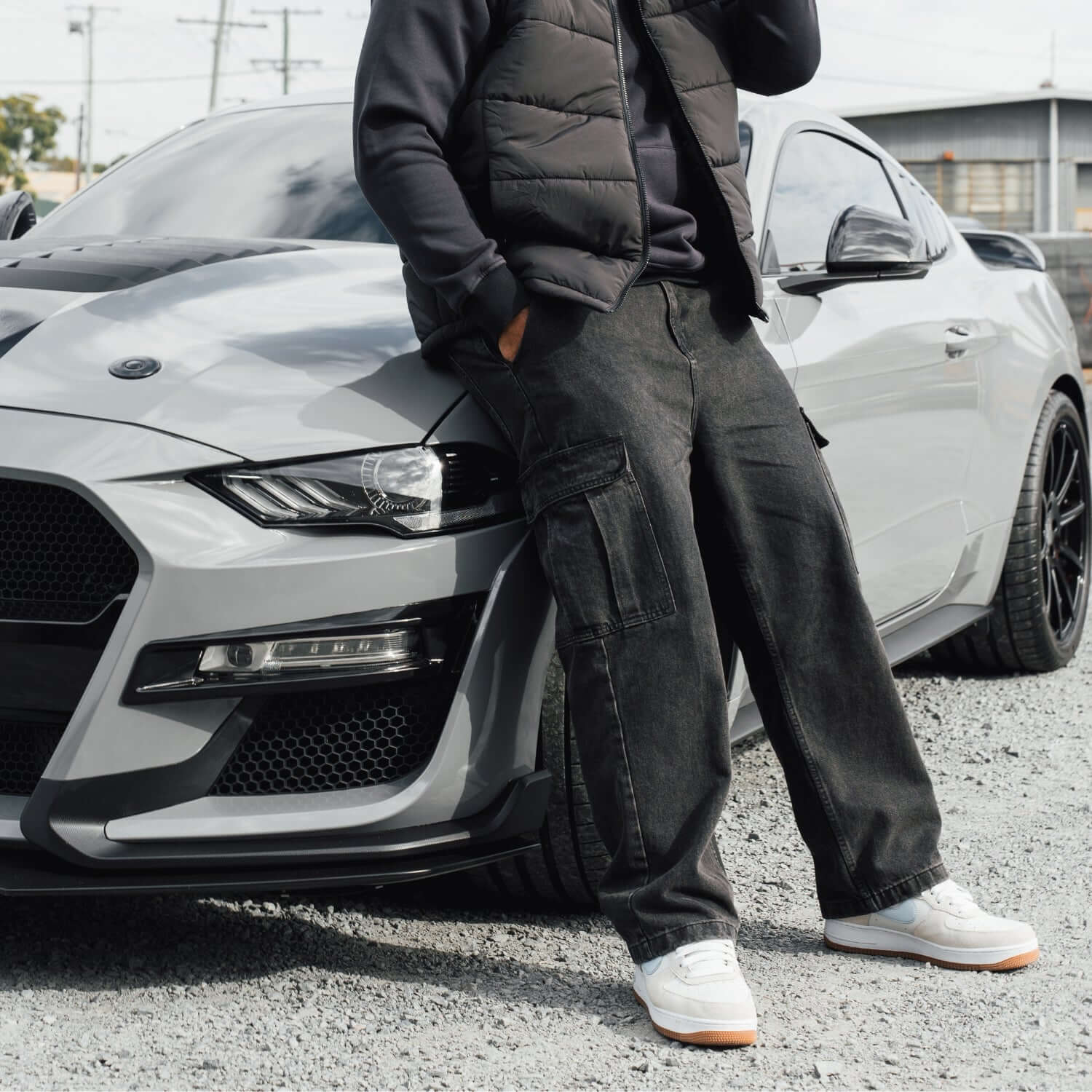 Person leaning against a gray car in an urban setting