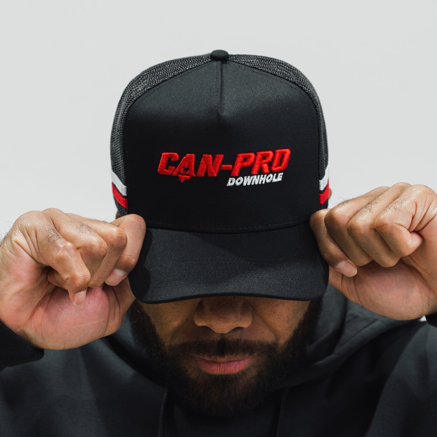 Person wearing a black cap with 'CAN-PRO DOWNHOLE' branding on a light gray background