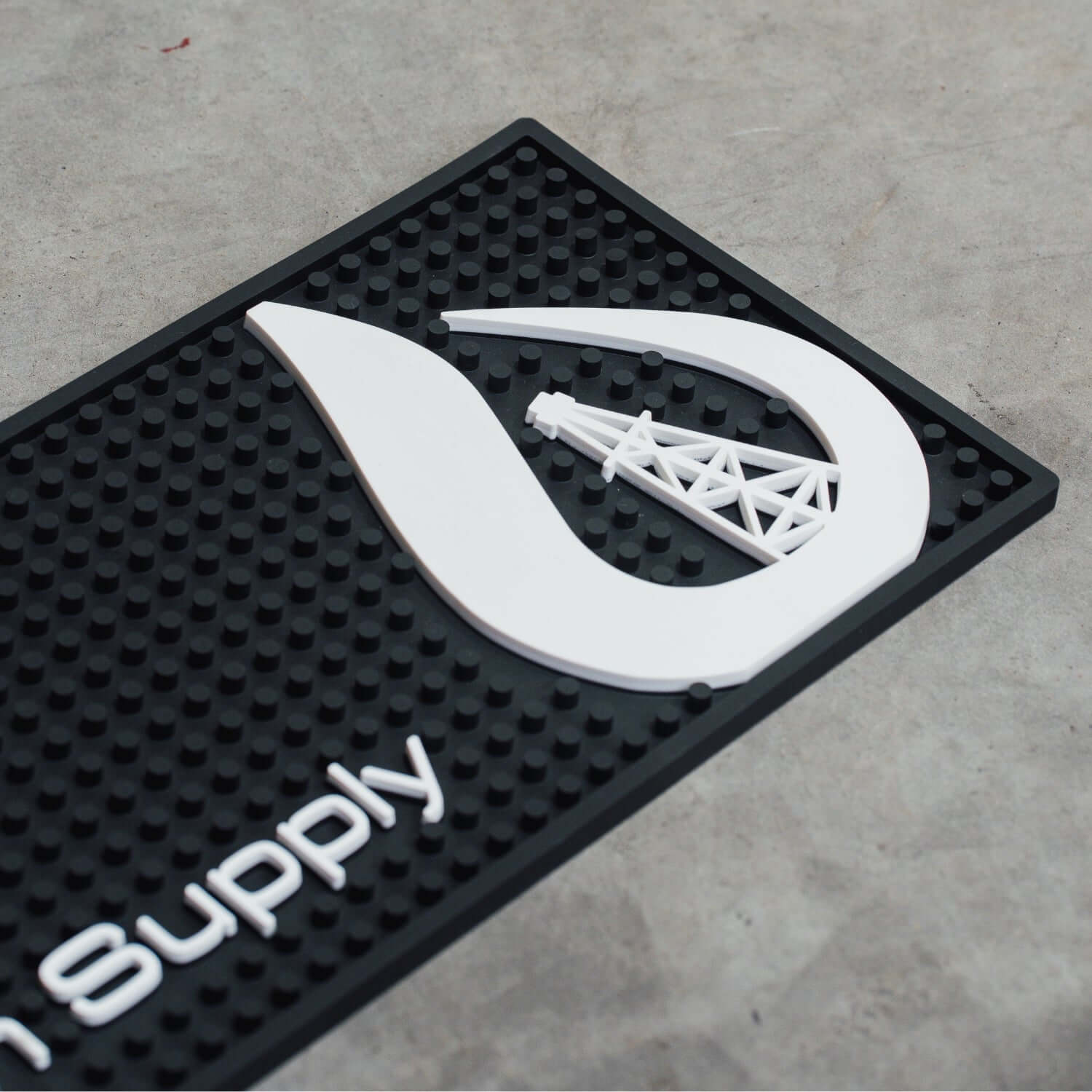 Black mat with white logo and 'Supply' text on a concrete floor