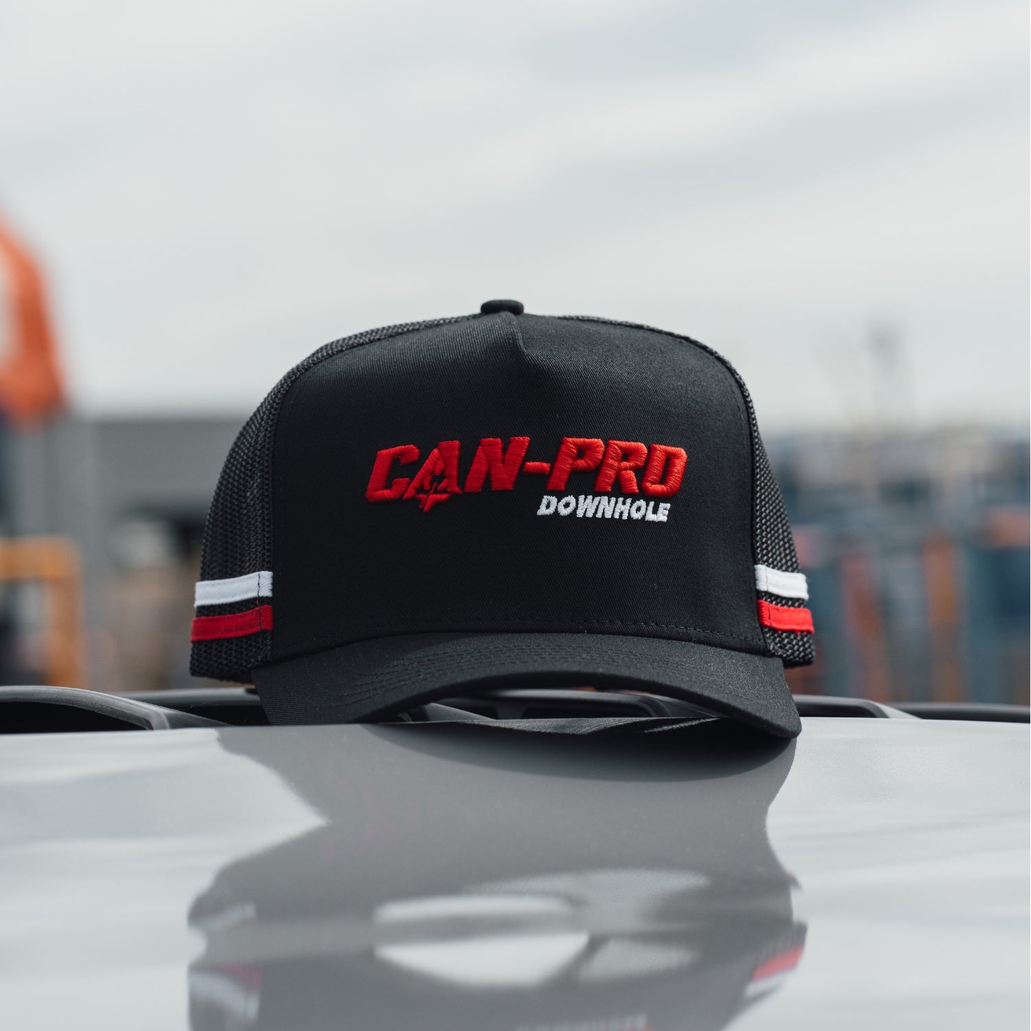 Black cap with 'CAN-PRO DOWNHOLE' text on a car hood