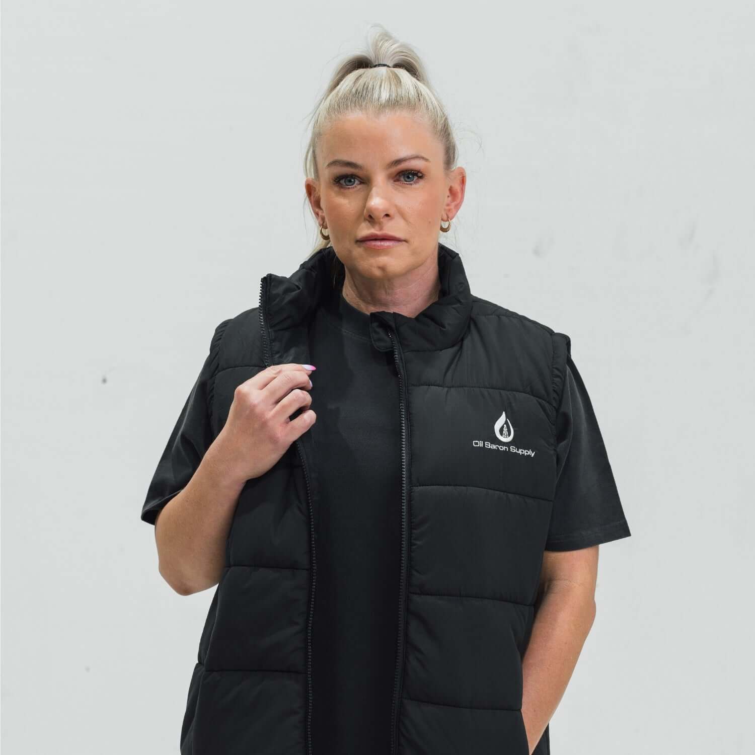 Person wearing a black puffer vest with a logo on a light gray background