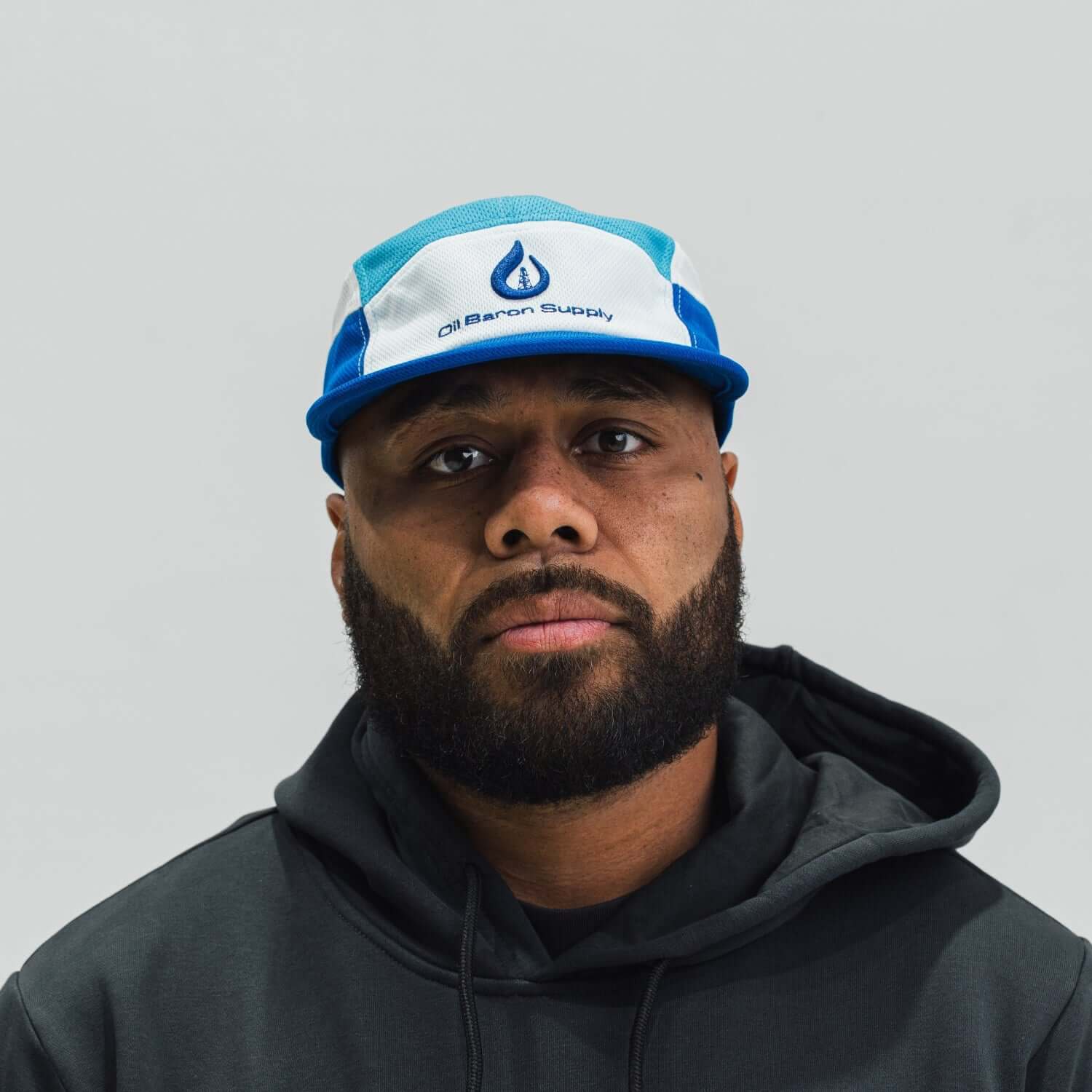 Man wearing a blue and white cap with a logo on a gray background