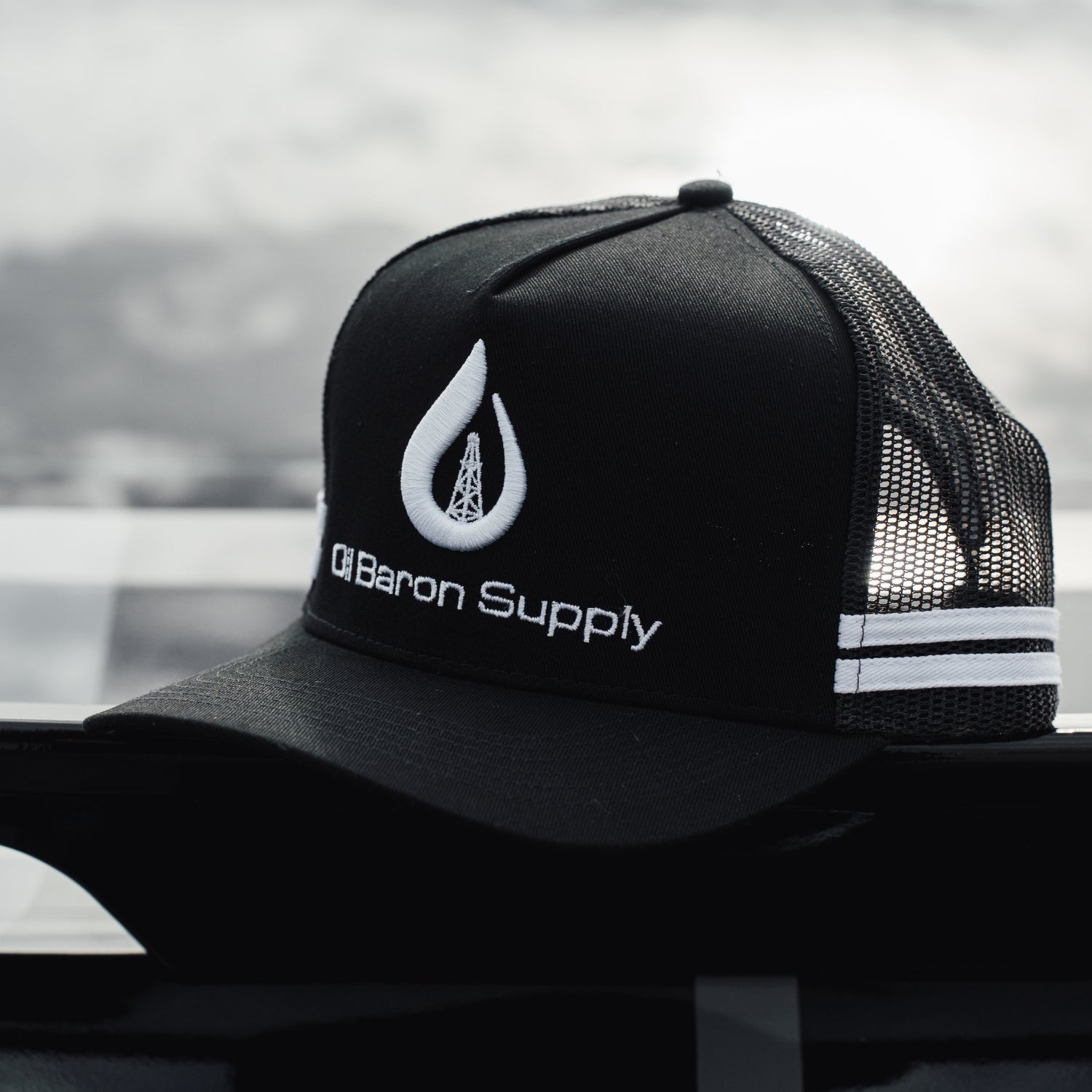 Black cap with mesh back and Oil Baron Supply logo on a blurred background