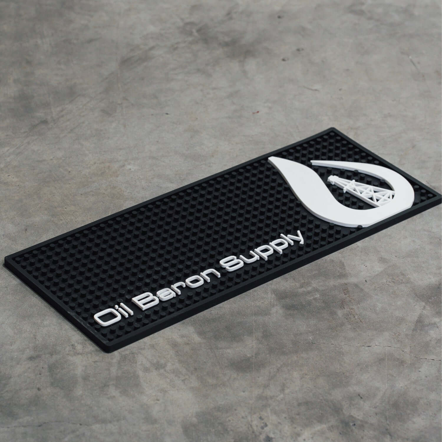 Black mat with white logo and text on a gray concrete floor