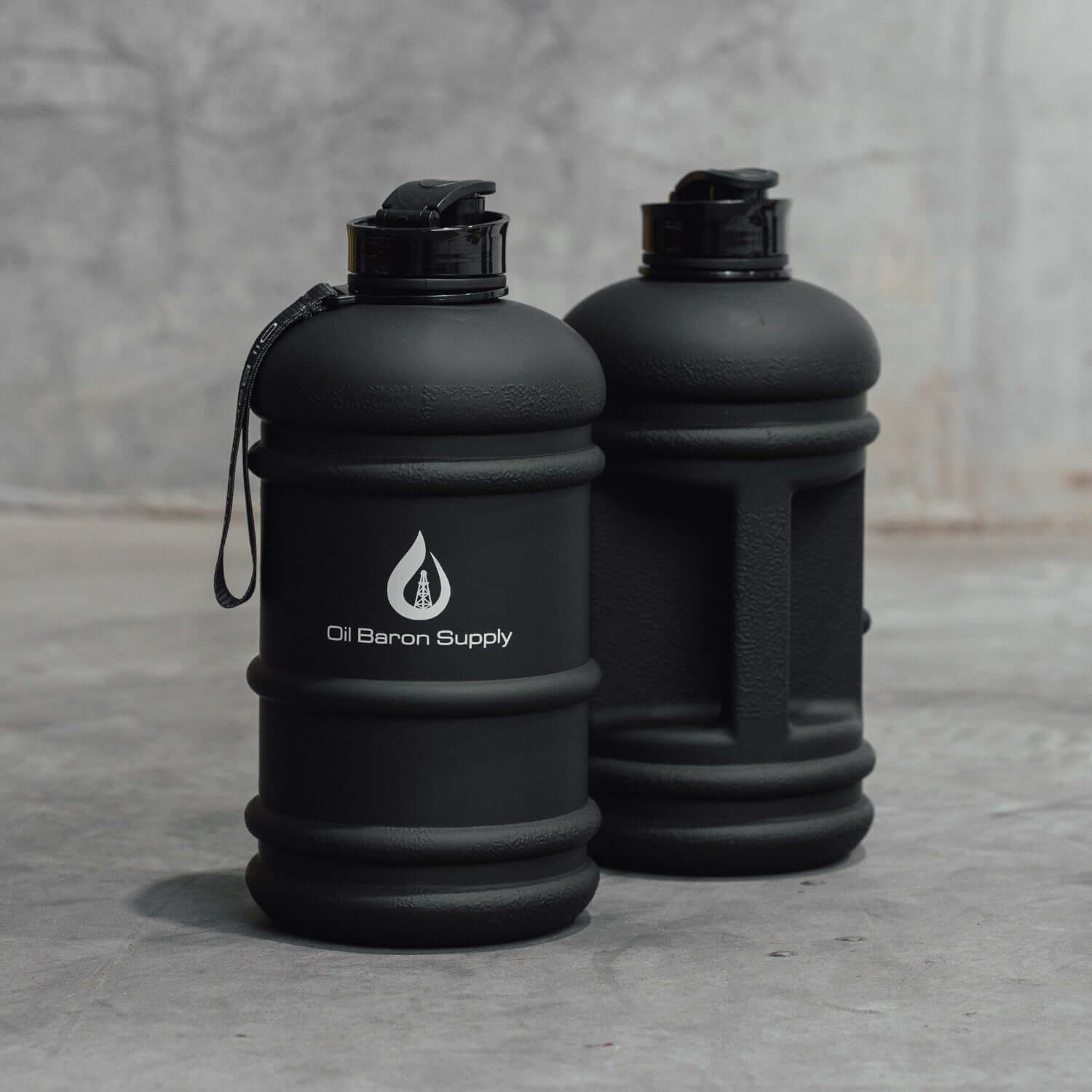 Two black water bottles with a visible oil baron supply logo on a gray surface