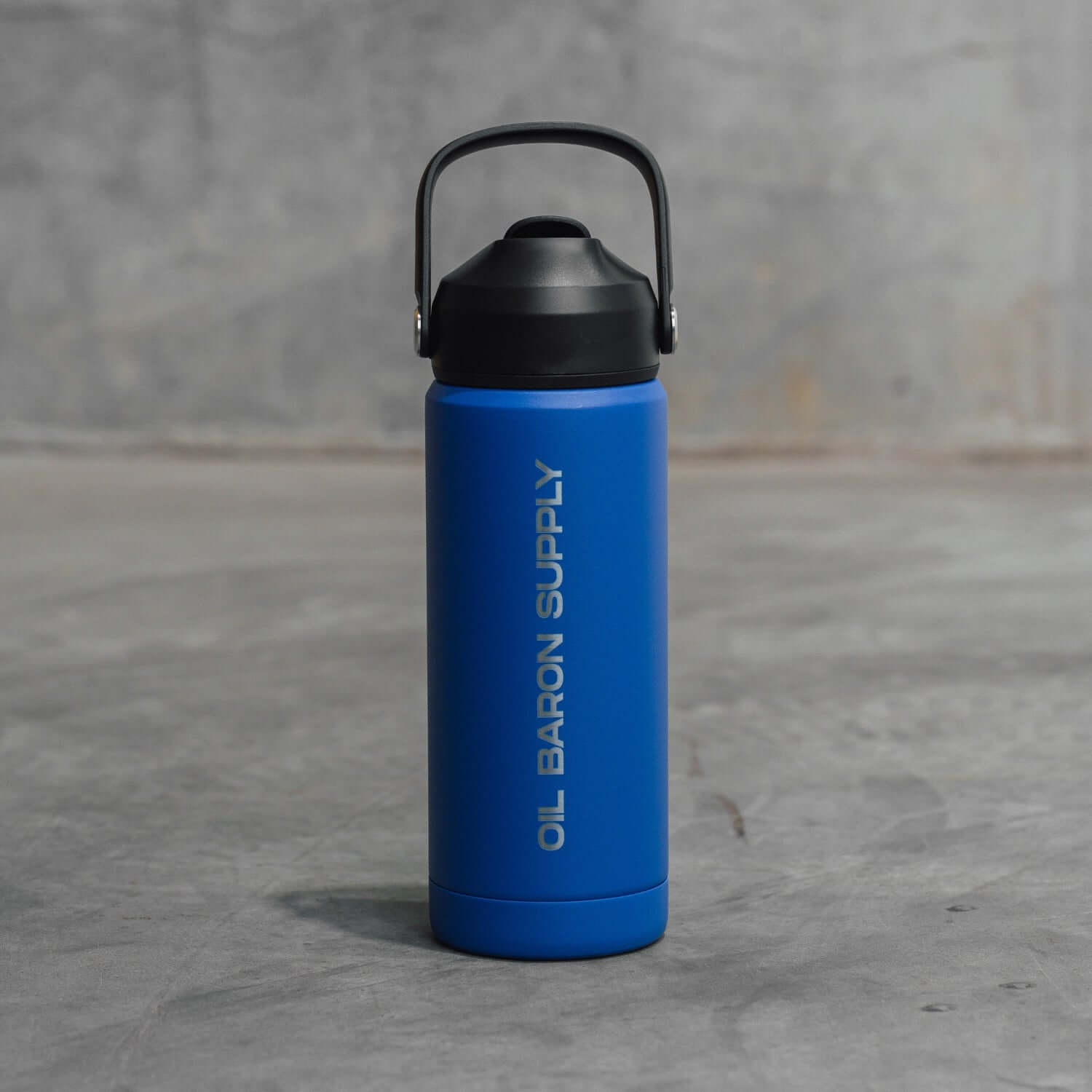 Blue insulated bottle with black lid on a gray surface with oil baron supply logo