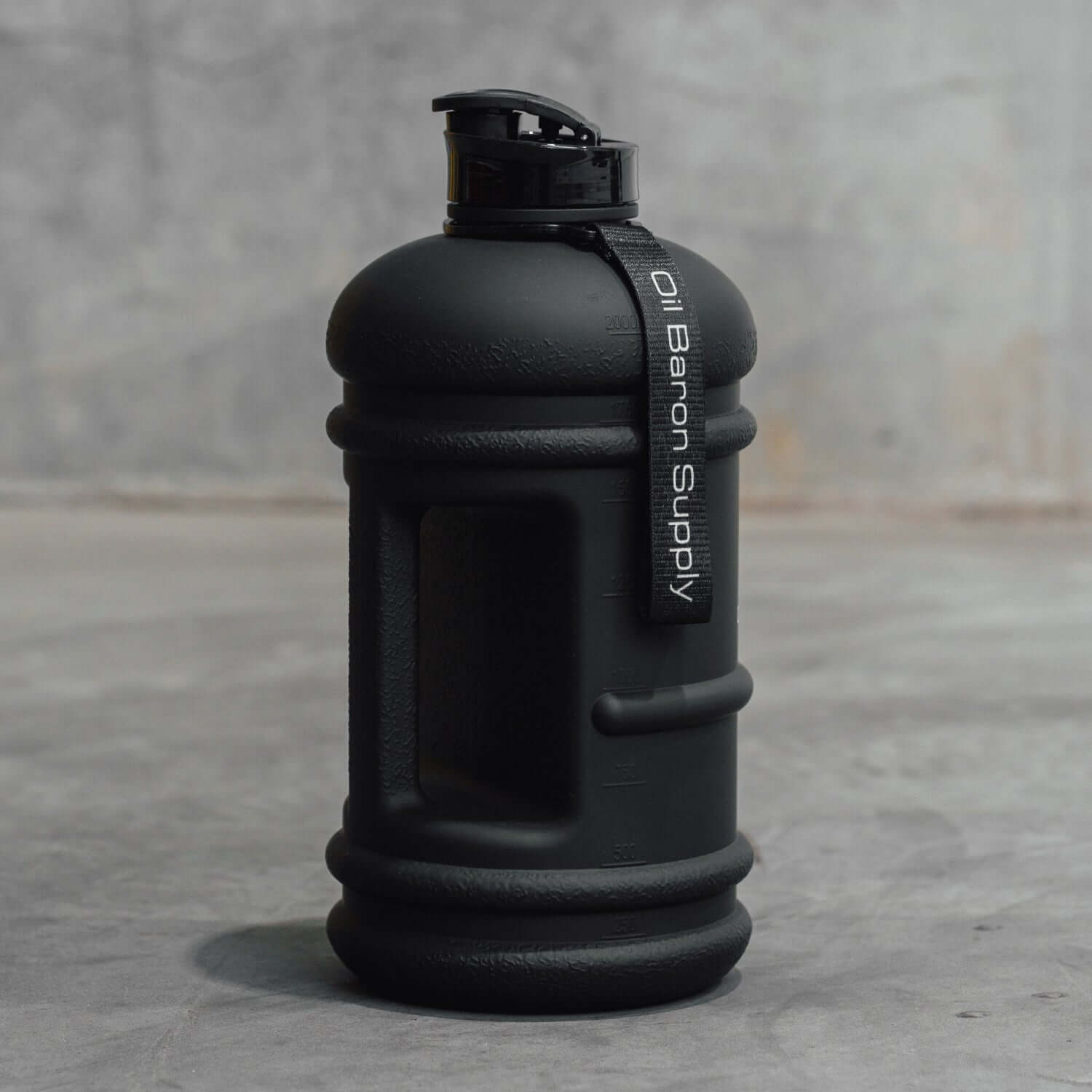 Black water bottle with 'Oil Baron Supply' label on a gray surface