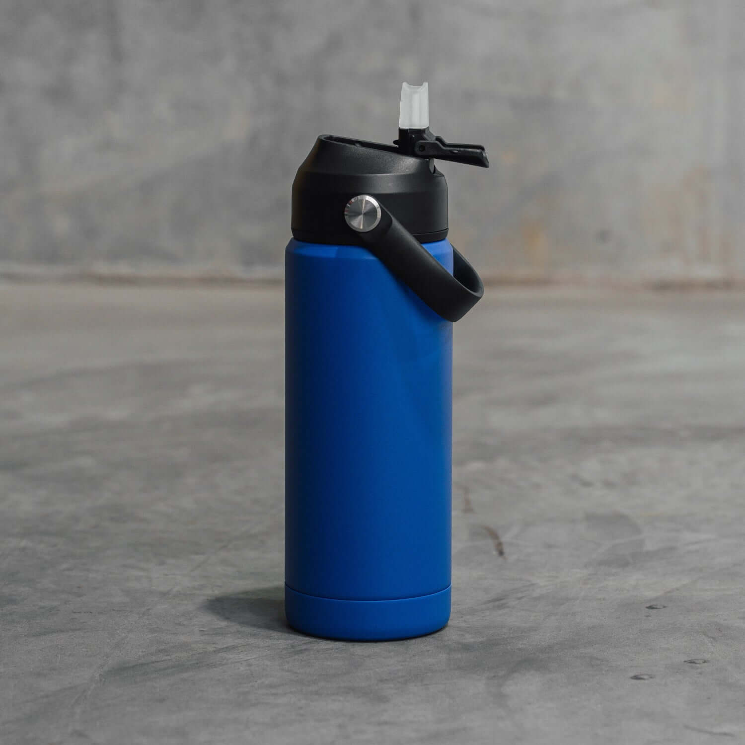 Blue insulated bottle with black lid on a gray surface