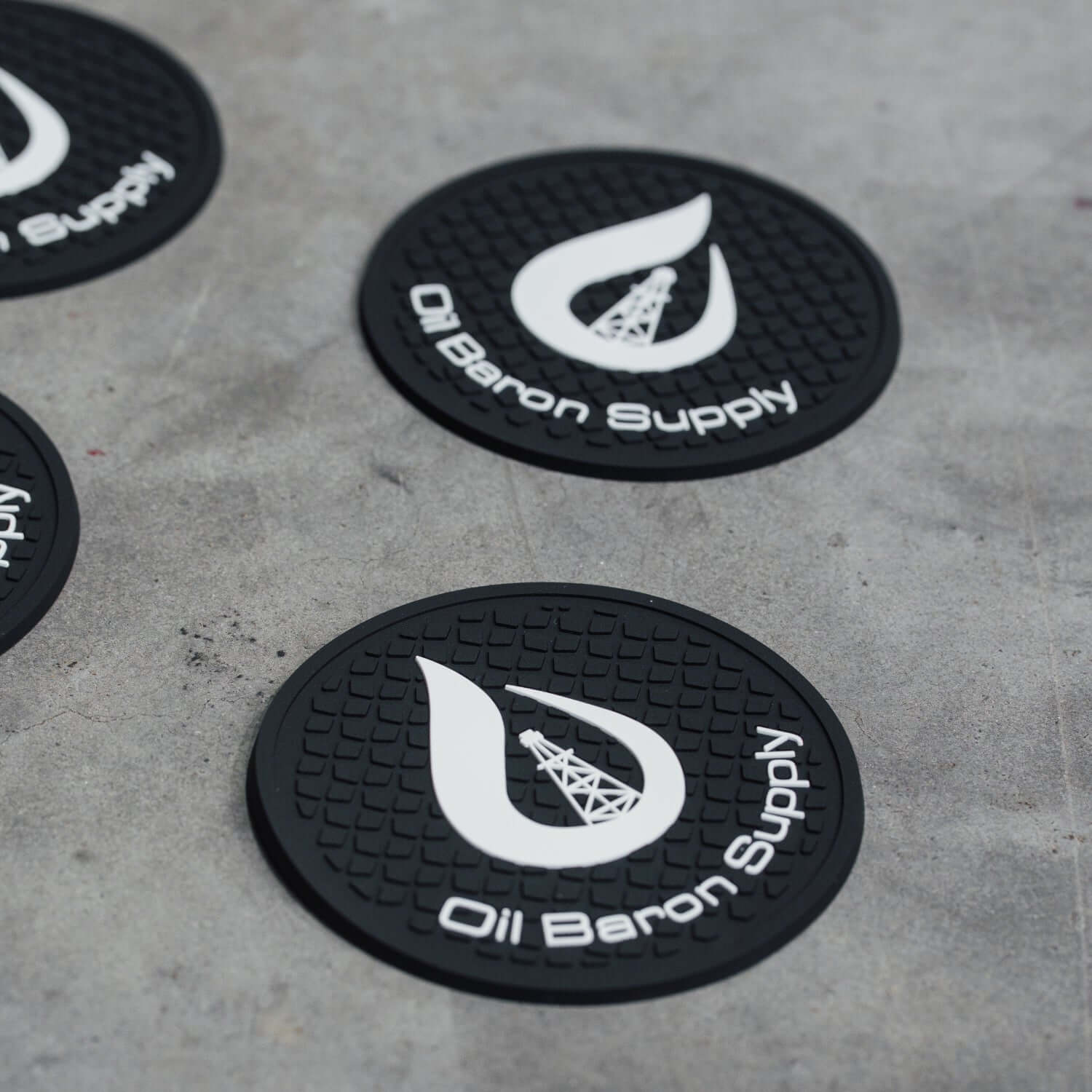Black rubber mats with 'Oil Baron Supply' logo on a concrete surface