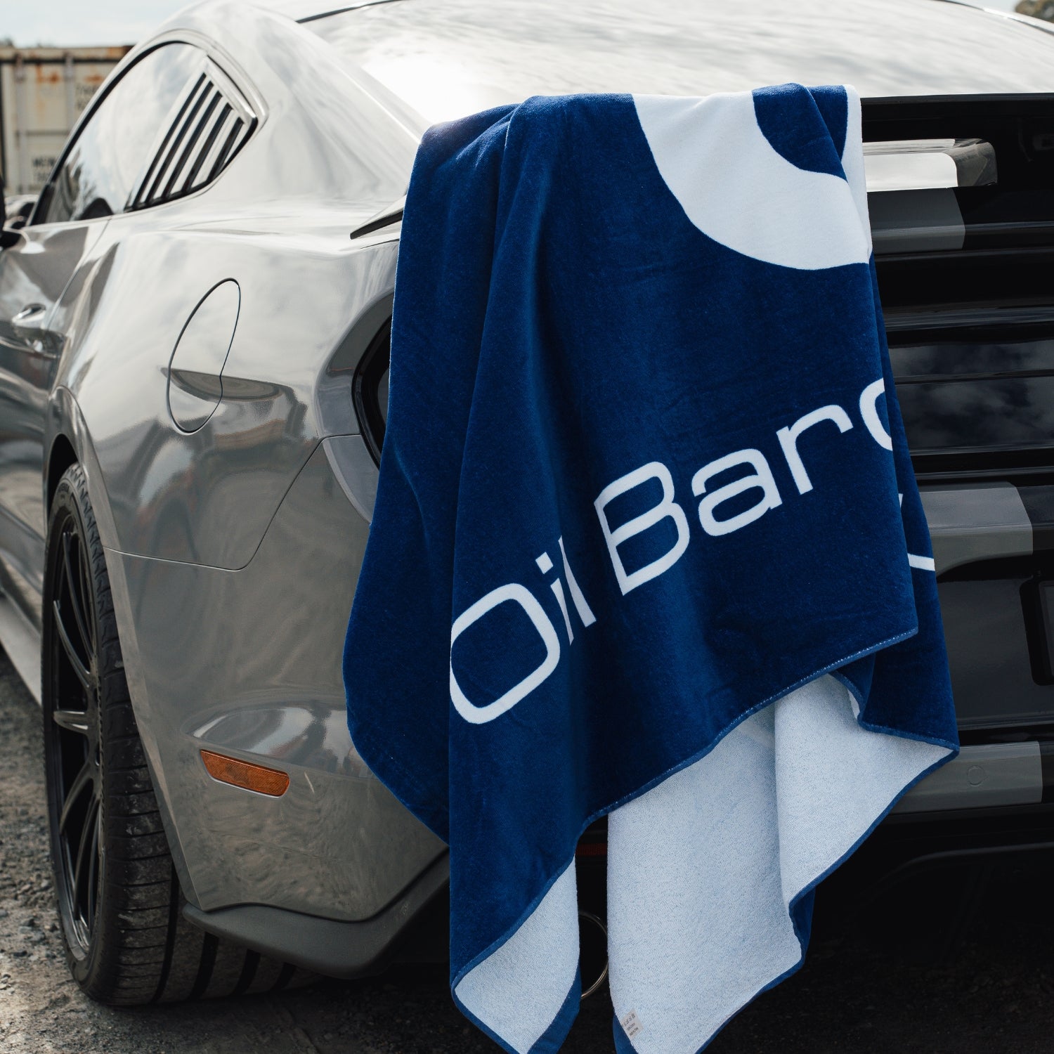 Blue towel with 'Oil Baron Supply' logo draped over a car